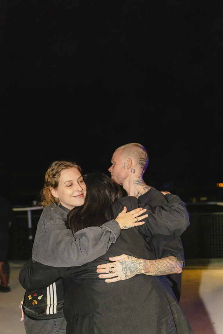 Three friends sharing a warm hug at a night event at at06 in Canggu.