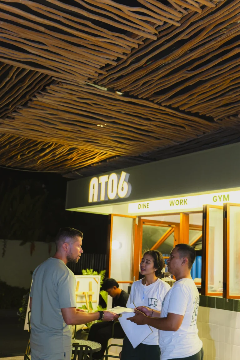 A man interacting with at06 staff members at night in Canggu, Bali.