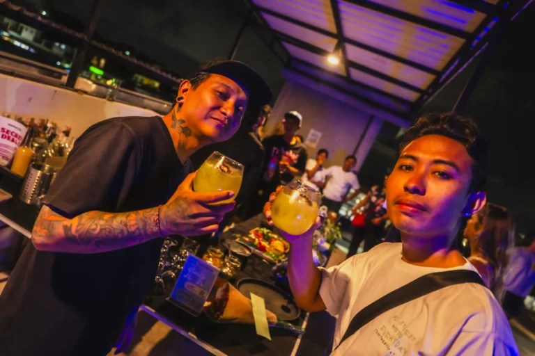 Two men enjoying cocktails at a night event at AT 06 in Canggu.