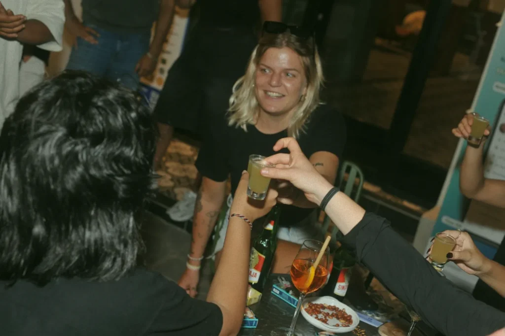A group of friends cheering with shots at an event at 06 in Canggu, Bali, enjoying the vibrant nightlife and community atmosphere.