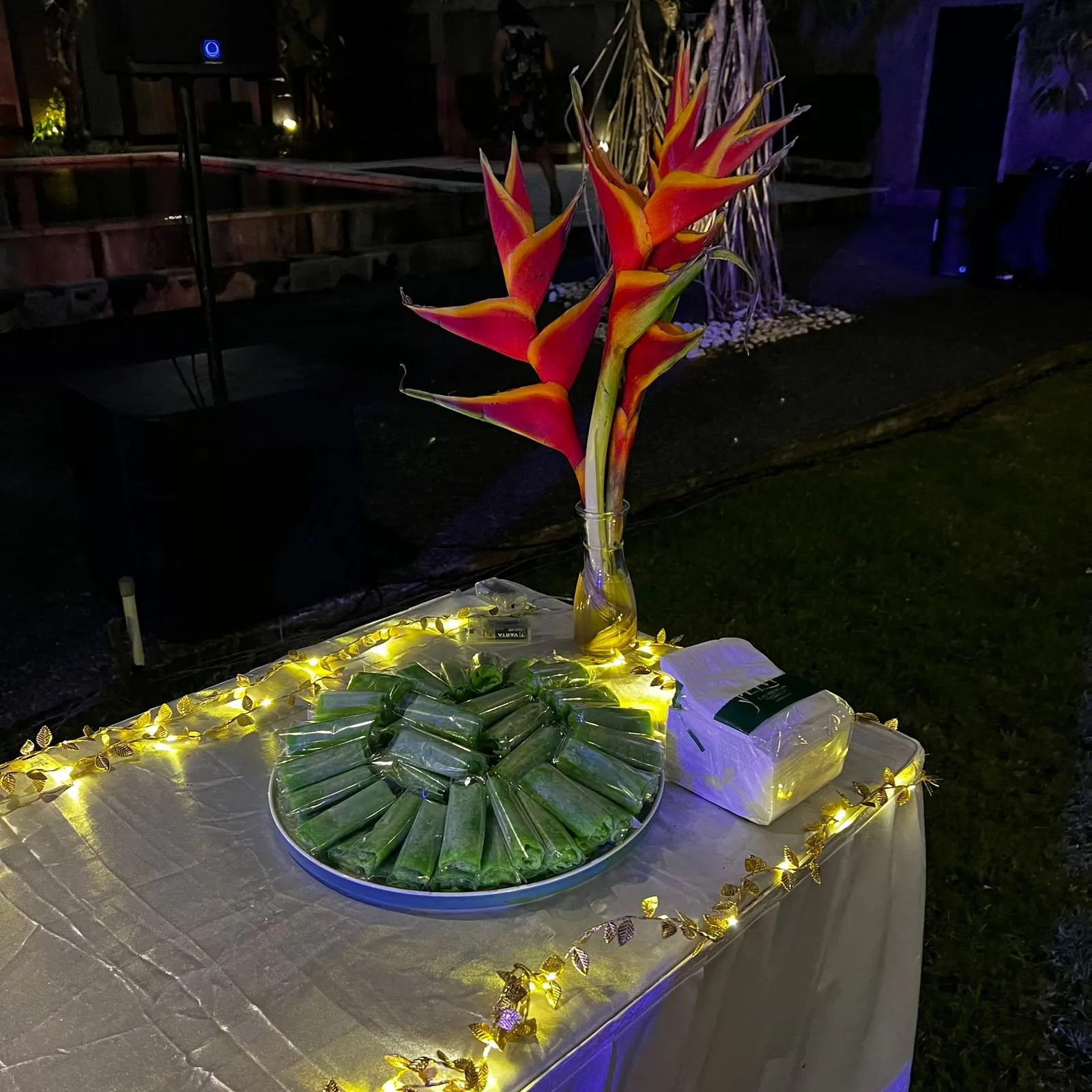 A decorated table at an evening event at AT06 in Canggu, with Heliconia flowers and desserts.
