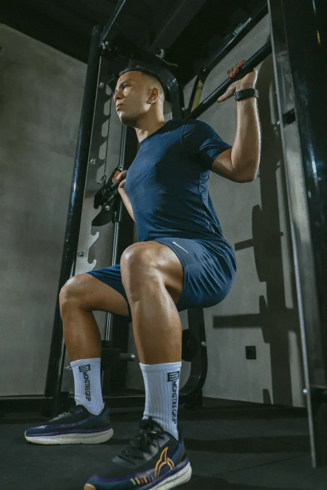 A man performing a barbell squat at a gym in Canggu, demonstrating proper form and dedication to fitness.