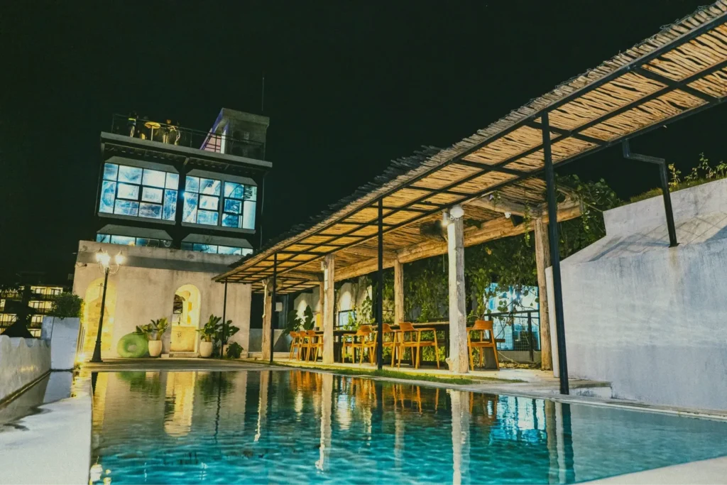 The modern at 06 building in Canggu at night, with its lights reflected in the swimming pool.