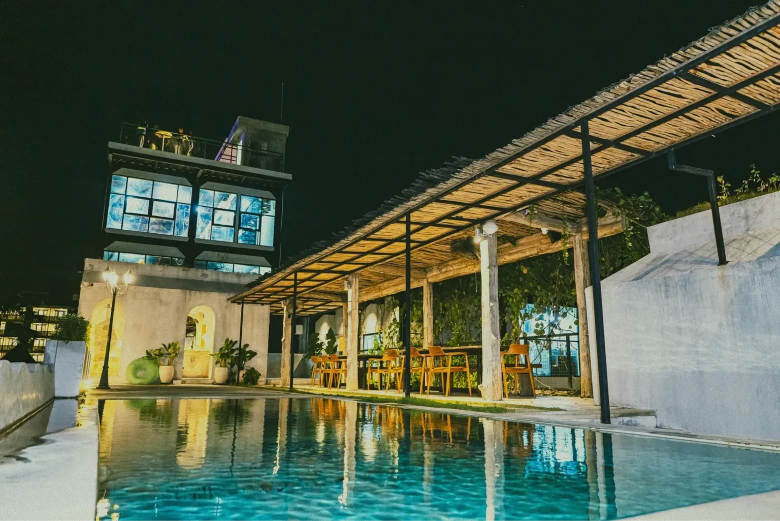 The modern at 06 building in Canggu at night, with its lights reflected in the swimming pool.