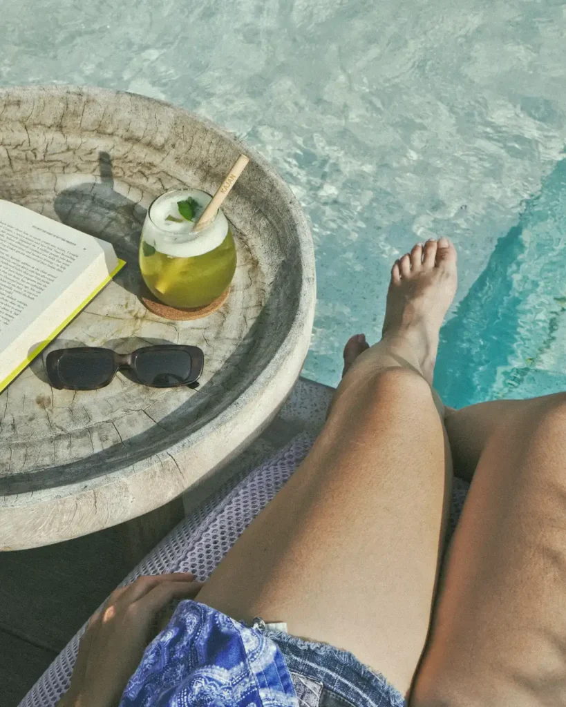 Woman relaxing by the pool at AT 06 Canggu Bali with a drink and a book